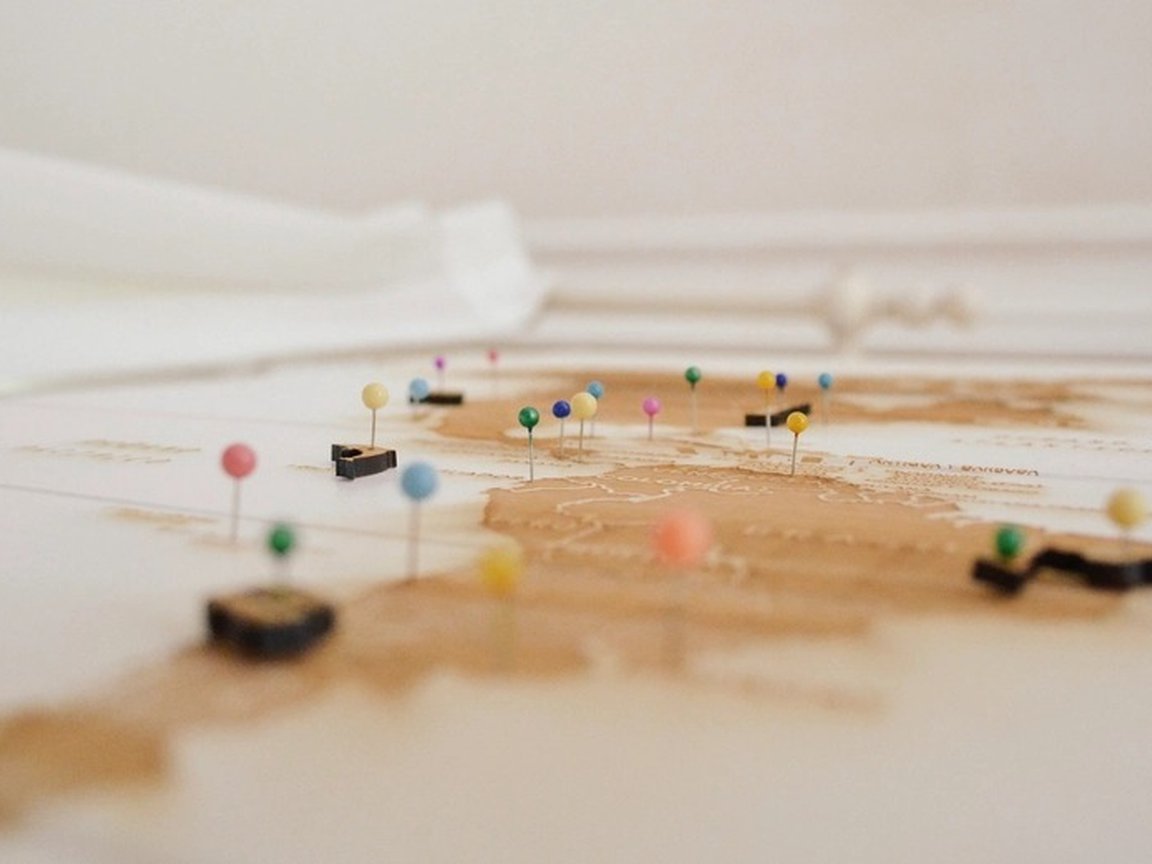 Colored pins marking several places on a soft-focus world map.